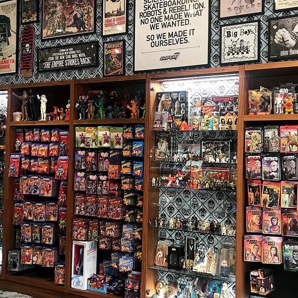 Inside a retro toy store packed with shelves of vintage action figures and collectibles.