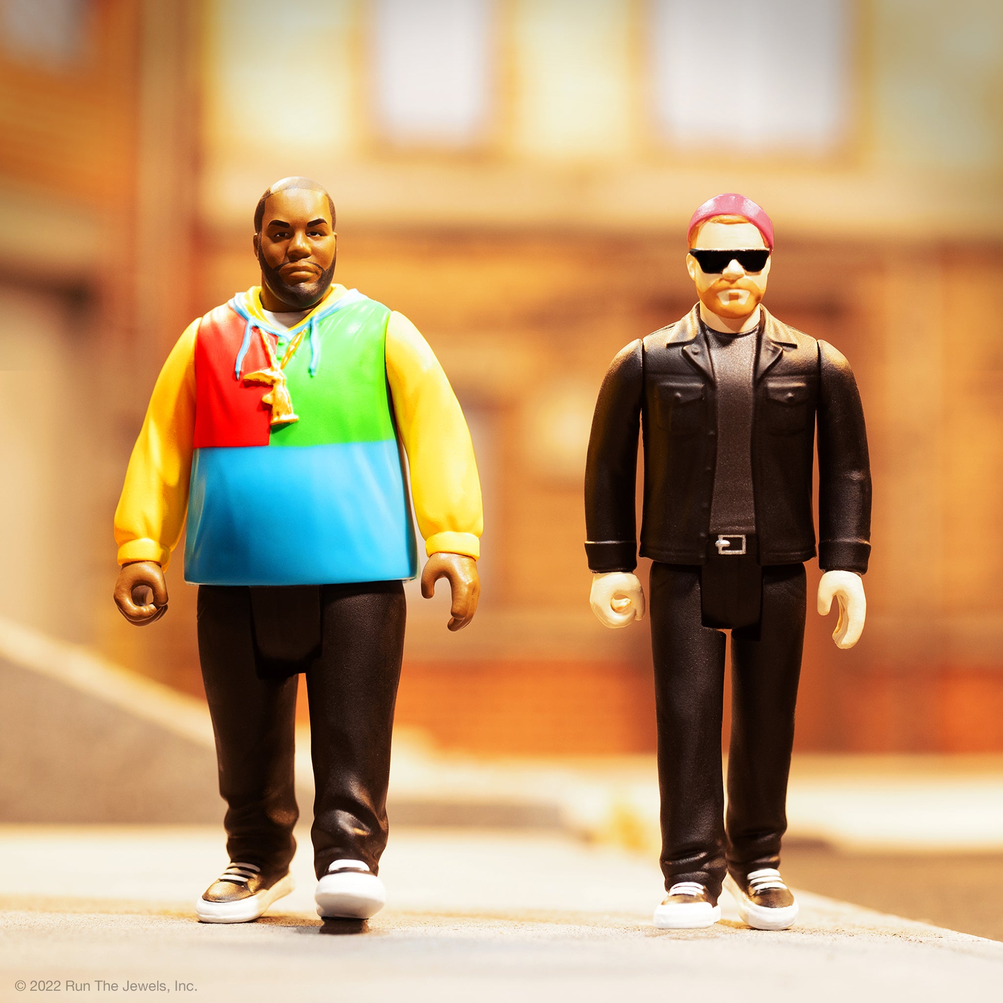 Run The Jewels ReAction Figures pair with one wearing a bright color block hoodie and the other in a black leather jacket with sunglasses