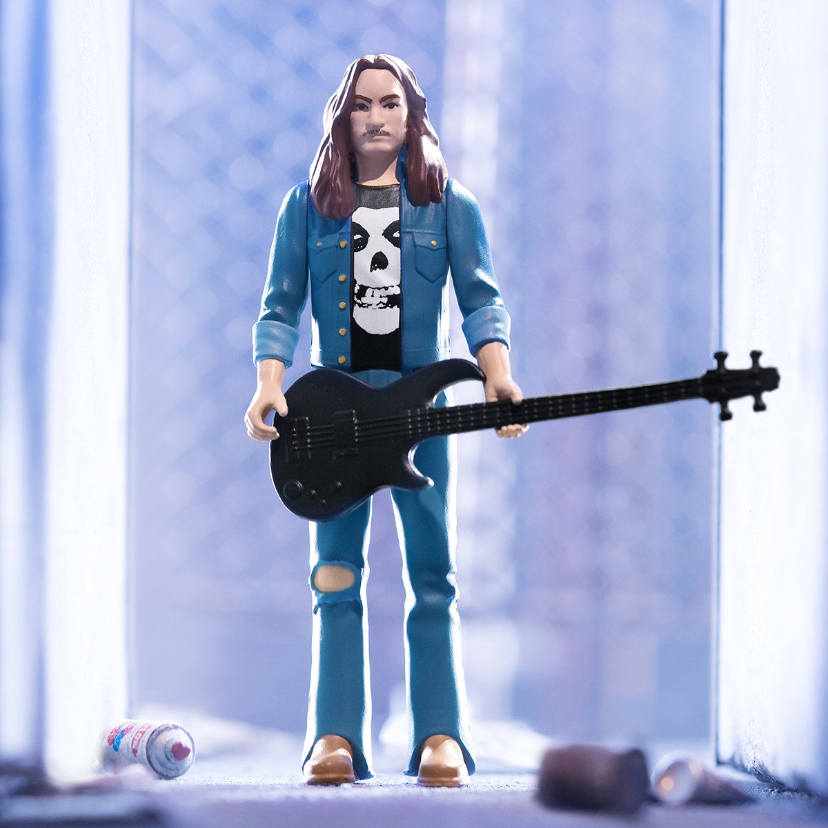Cliff Burton action figure in a blue jacket with skull shirt holding a black bass guitar.