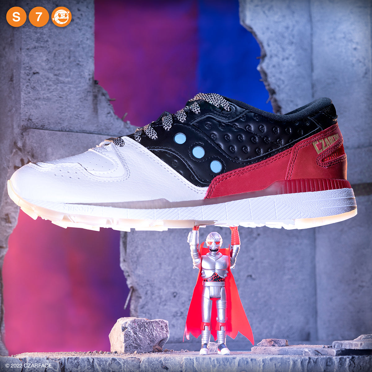 Saucony Azura sneaker in white black and red suspended above a small robot figure.