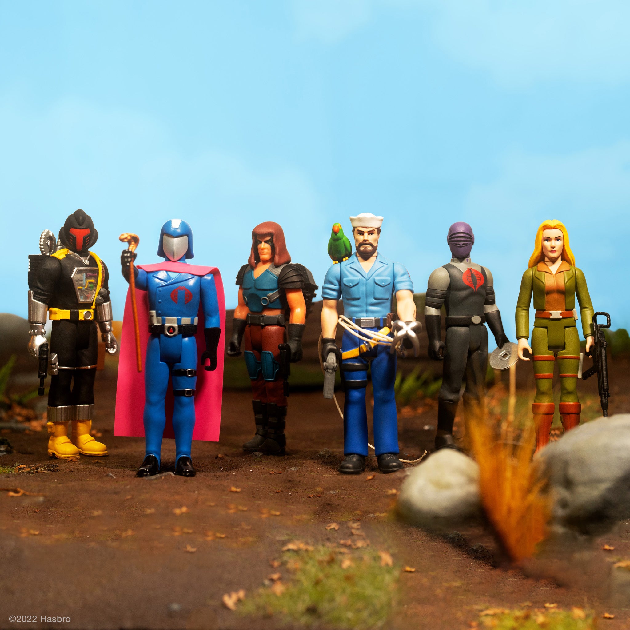 Lineup of GI Joe Wave 4 ReAction Figures standing on a dirt ground against a blue sky.