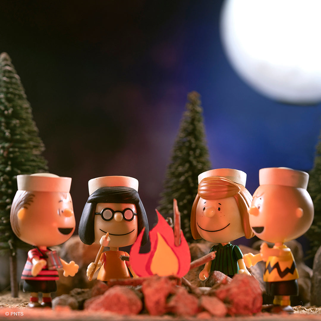 Peanuts mini figure diorama around a campfire in a forest at night with a large moon