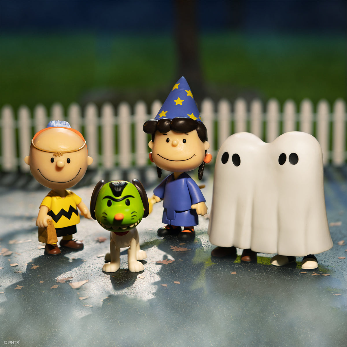 Peanuts characters in Halloween costumes with two white ghost figures on a spooky Halloween scene.