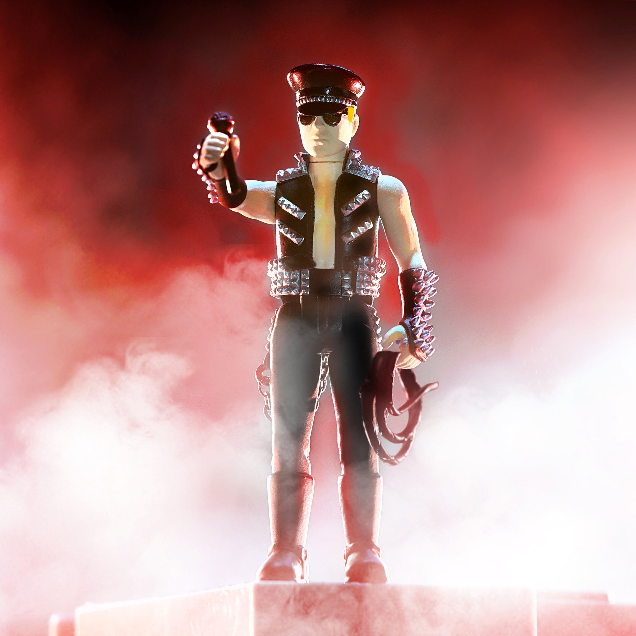 Heavy metal action figure wearing a black cap sunglasses and a studded vest on stage under red lighting