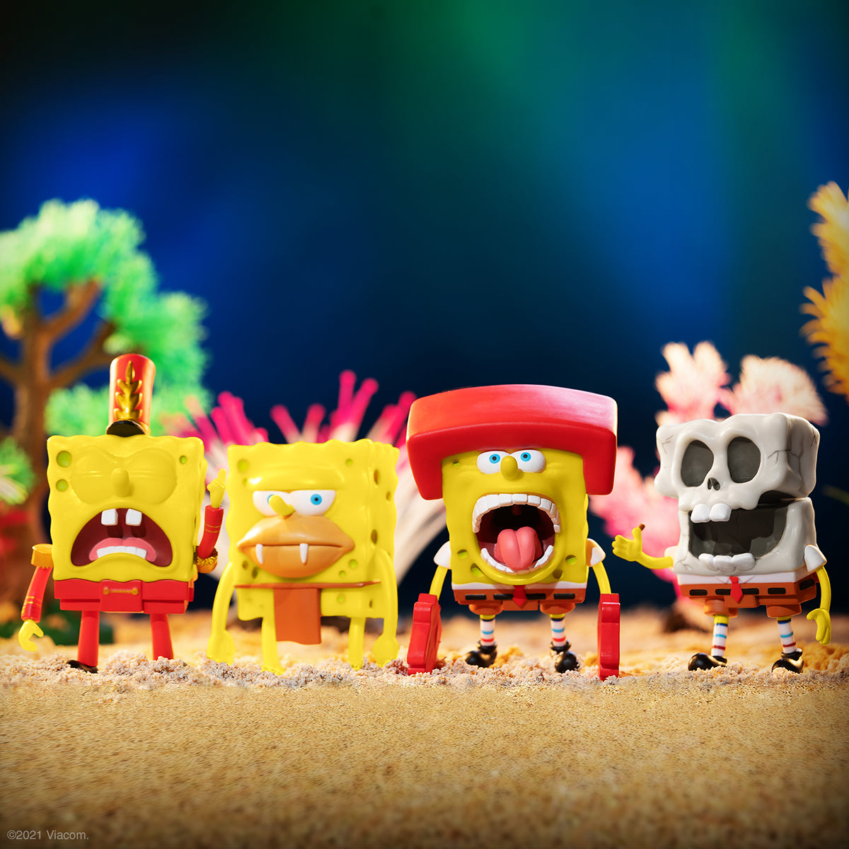 SpongeBob SquarePants Wave 2 ReAction figures lineup on a sandy surface featuring two yellow sponge characters and a skeleton figure