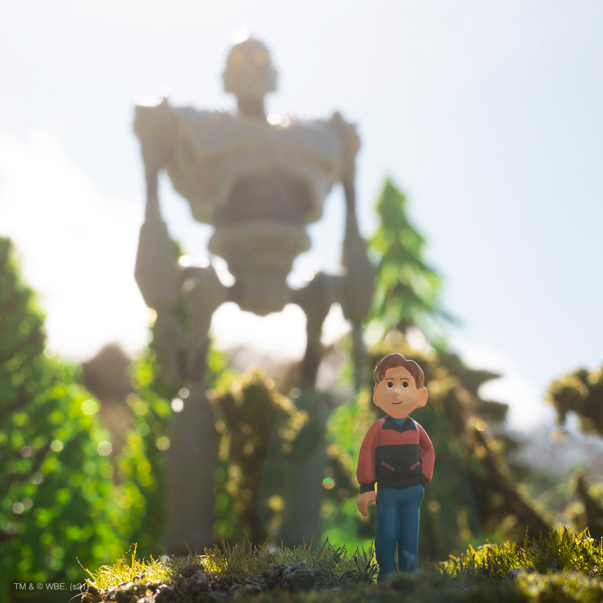 Small figure stands in the foreground as a large Iron Giant model towers behind in daylight.