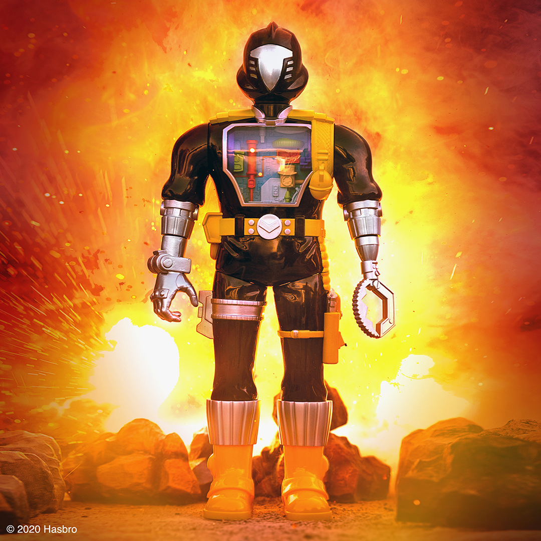 Super7 style action figure in a black suit with yellow harness and a transparent chest panel, standing amid a fiery background