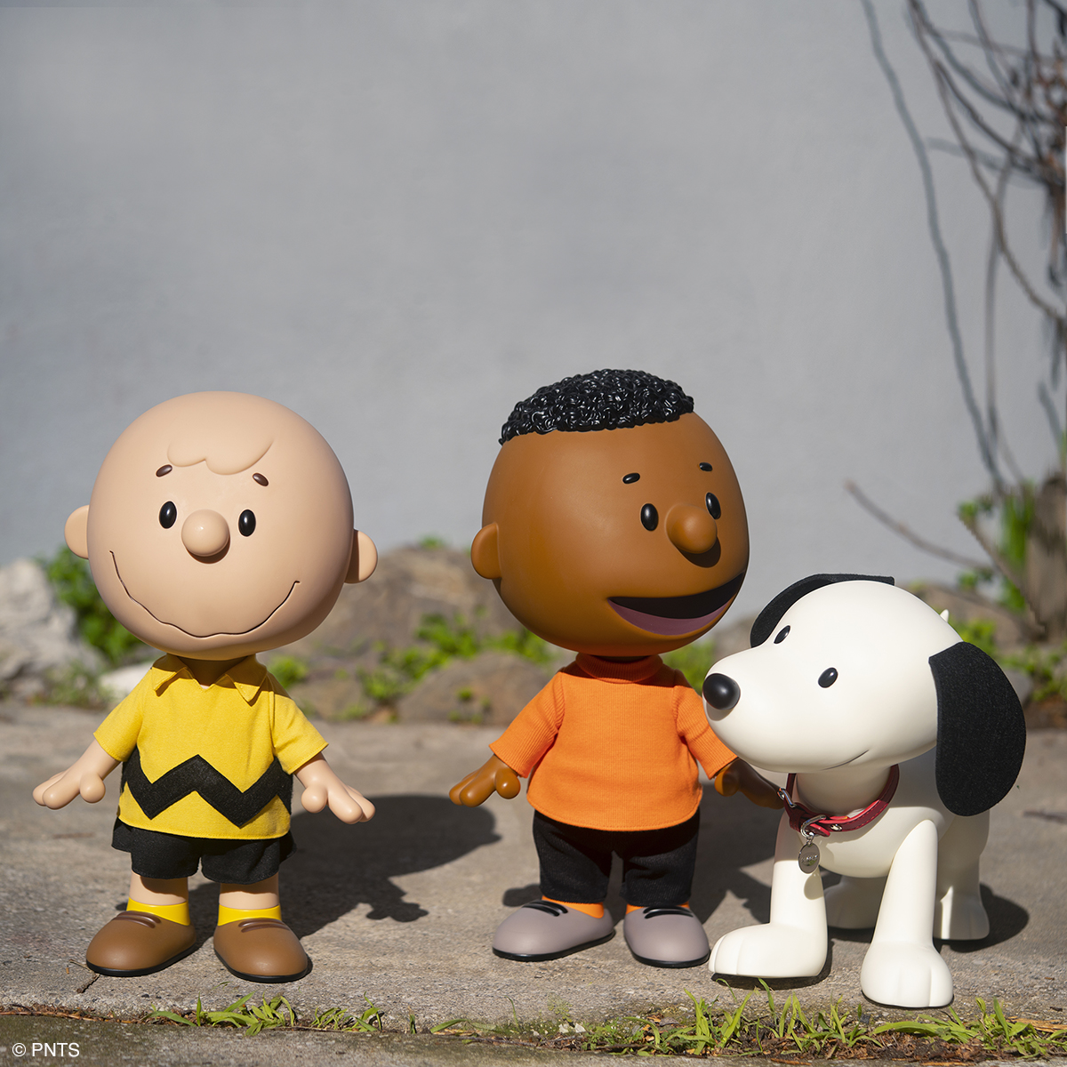 Charlie Brown Franklin and Snoopy oversized figures posed outdoors in a sunny scene.