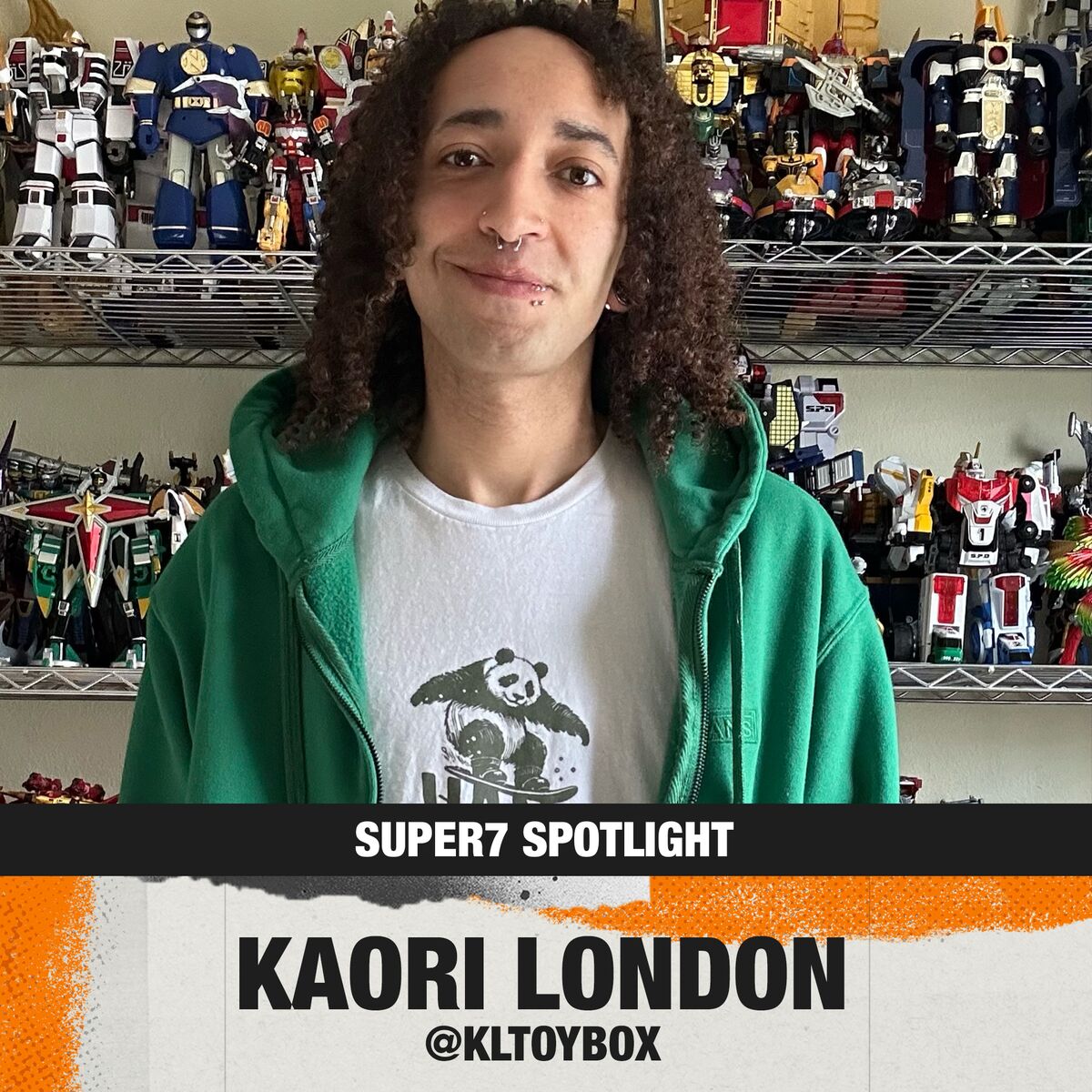 Portrait of Kaori London in a green hoodie and white panda tee, standing in front of shelves filled with vintage robot action figures.