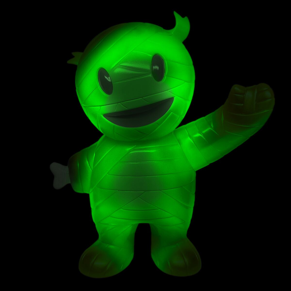 Glowing green mummy mascot with wrapped body and raised arm against a black background
