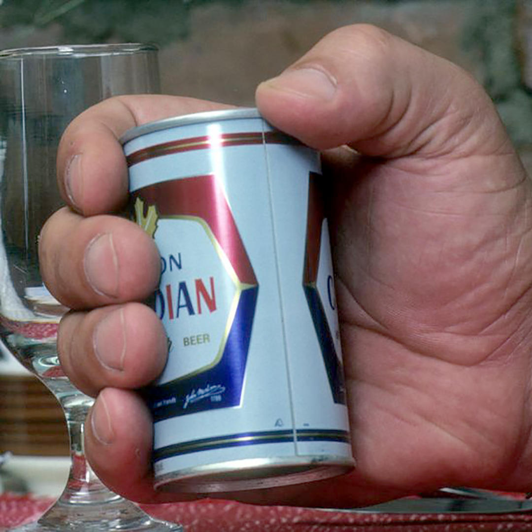 Close up of a hand gripping a can featuring André the Giant branding beside a glass.