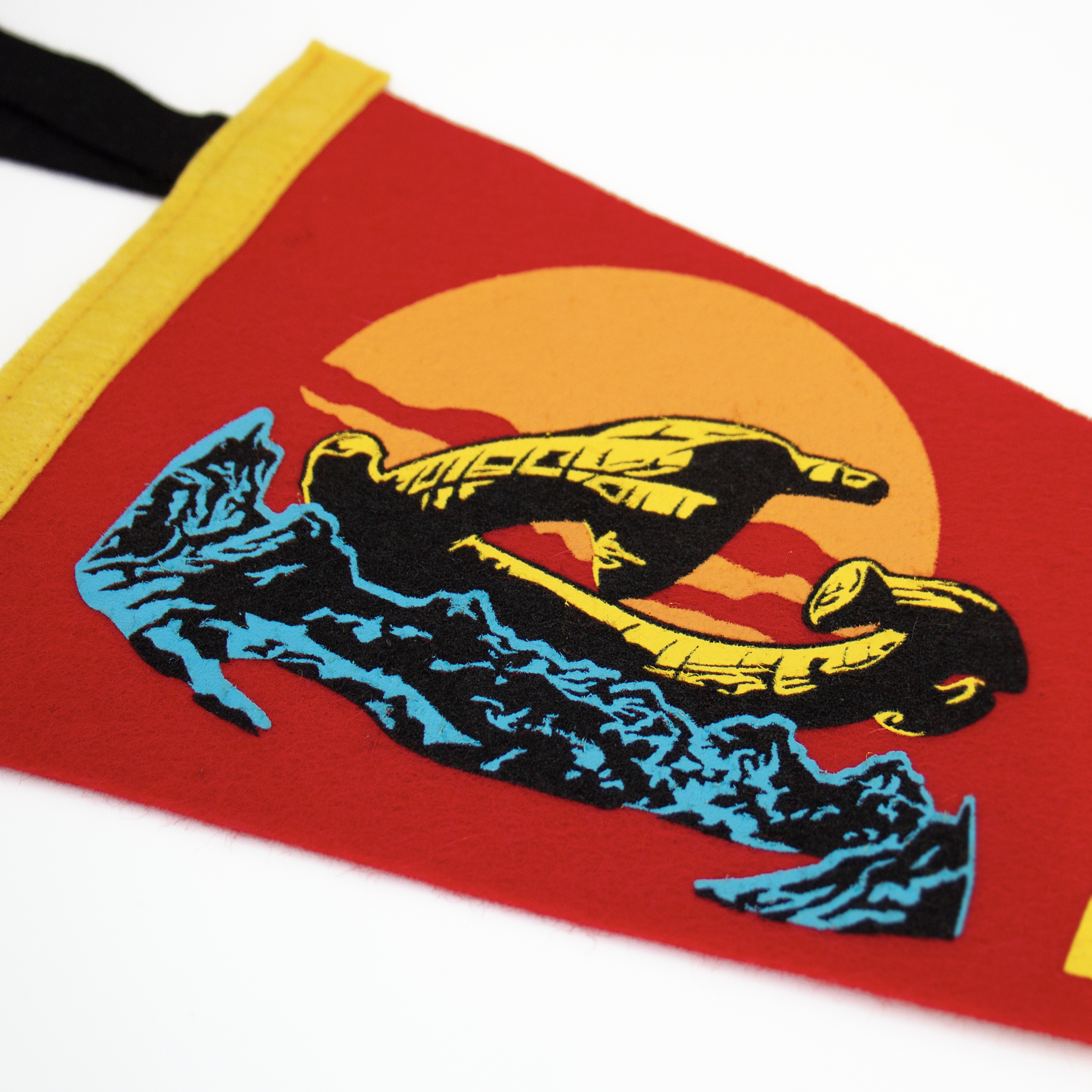 Close up of a red pennant with a yellow edge draped diagonally on a white background.