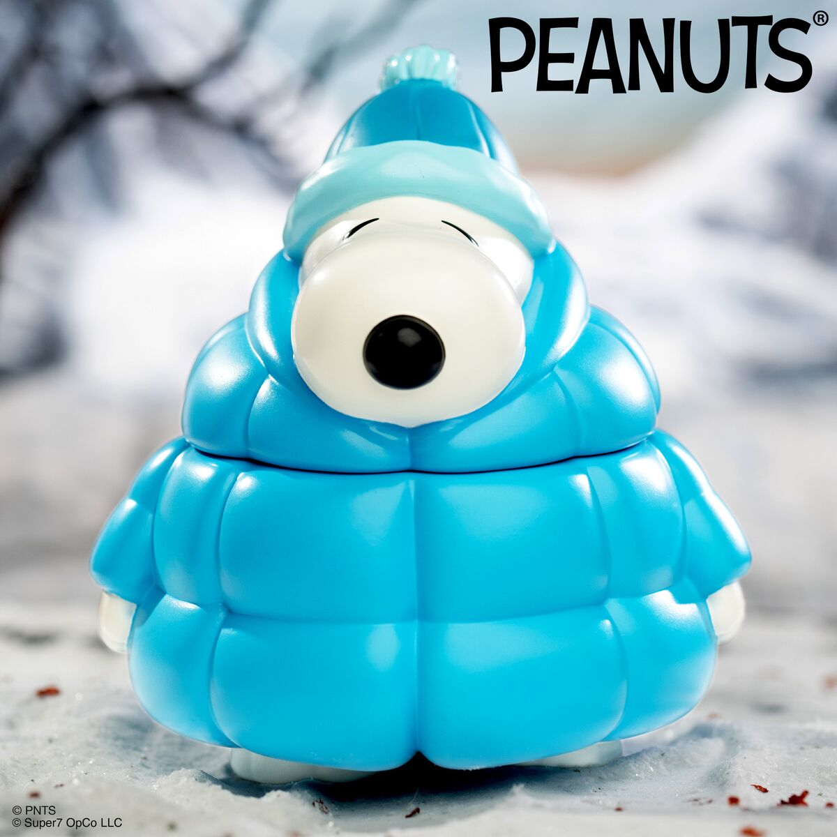 Blue cloud shaped Peanuts character figure with a large white face and black nose in a winter outfit.