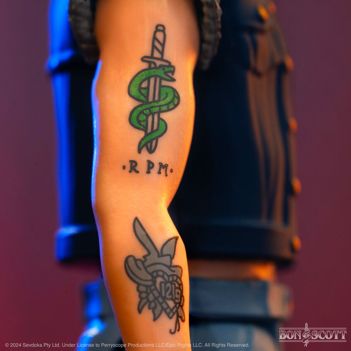 Tattooed forearm with a green snake wrapped around a dagger and RPM lettering.