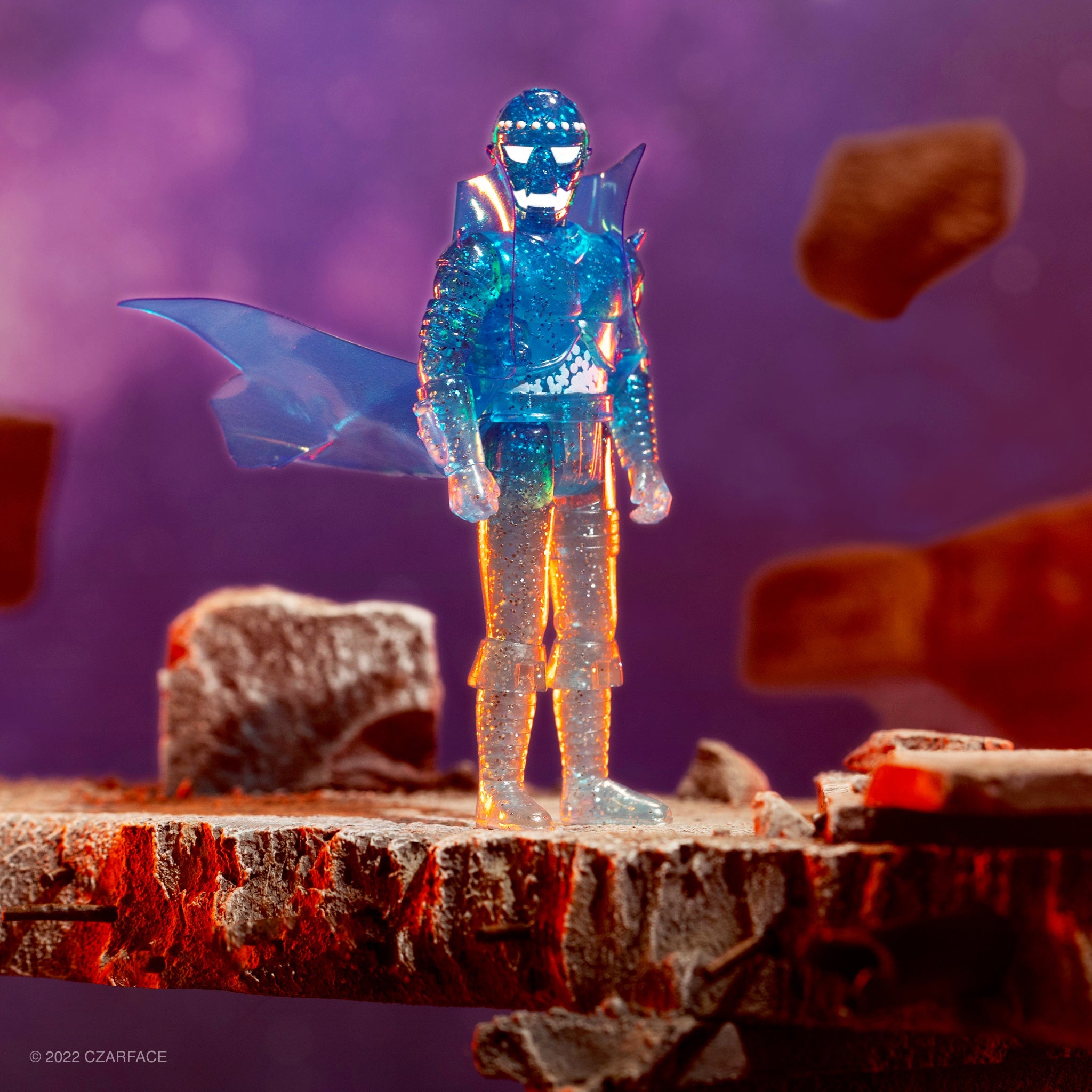 Translucent blue action figure with armor and a large winged accessory on a rocky pedestal against a purple backdrop.