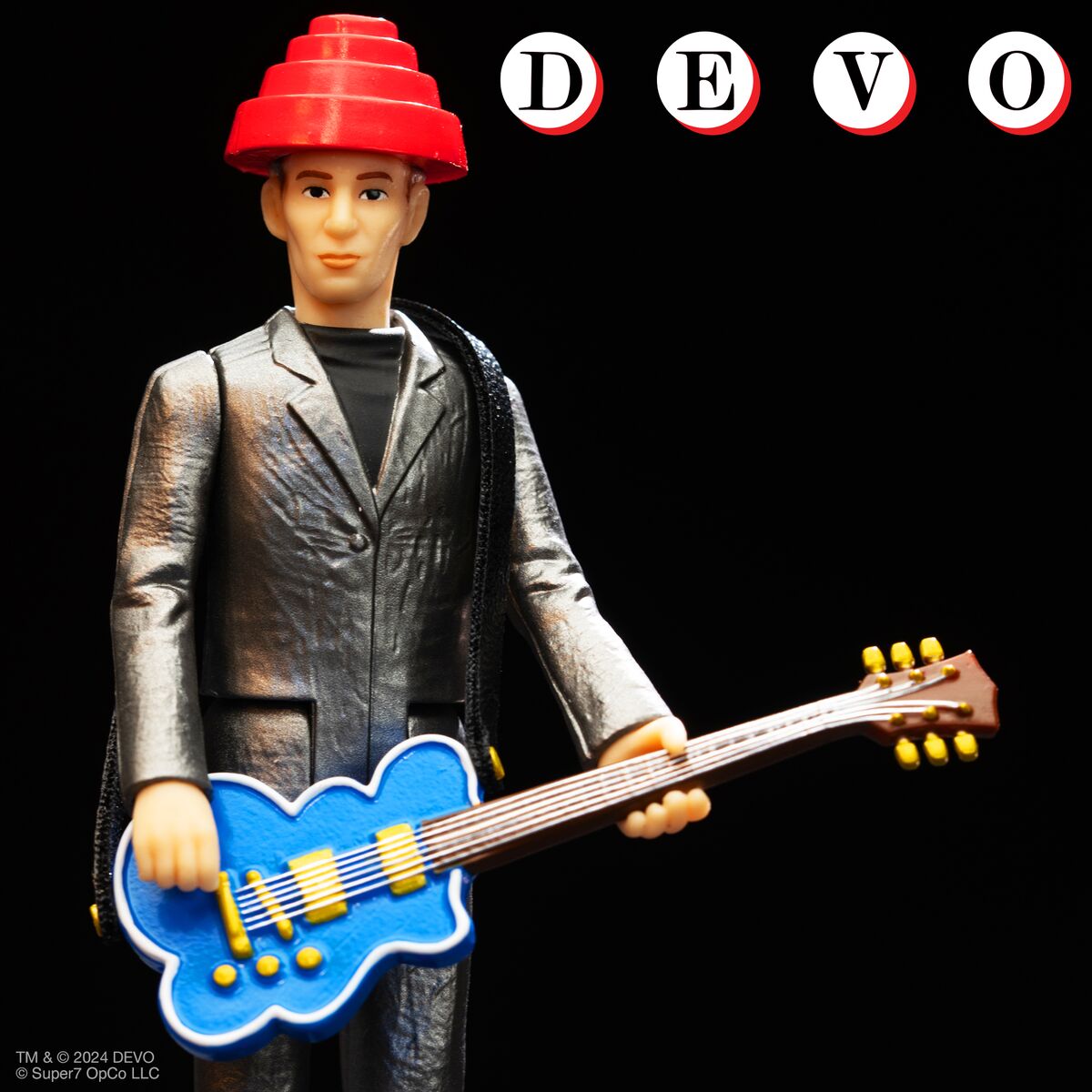 Action figure of a Devo member in a metallic silver suit and red conical hat holding a blue guitar against a black background.