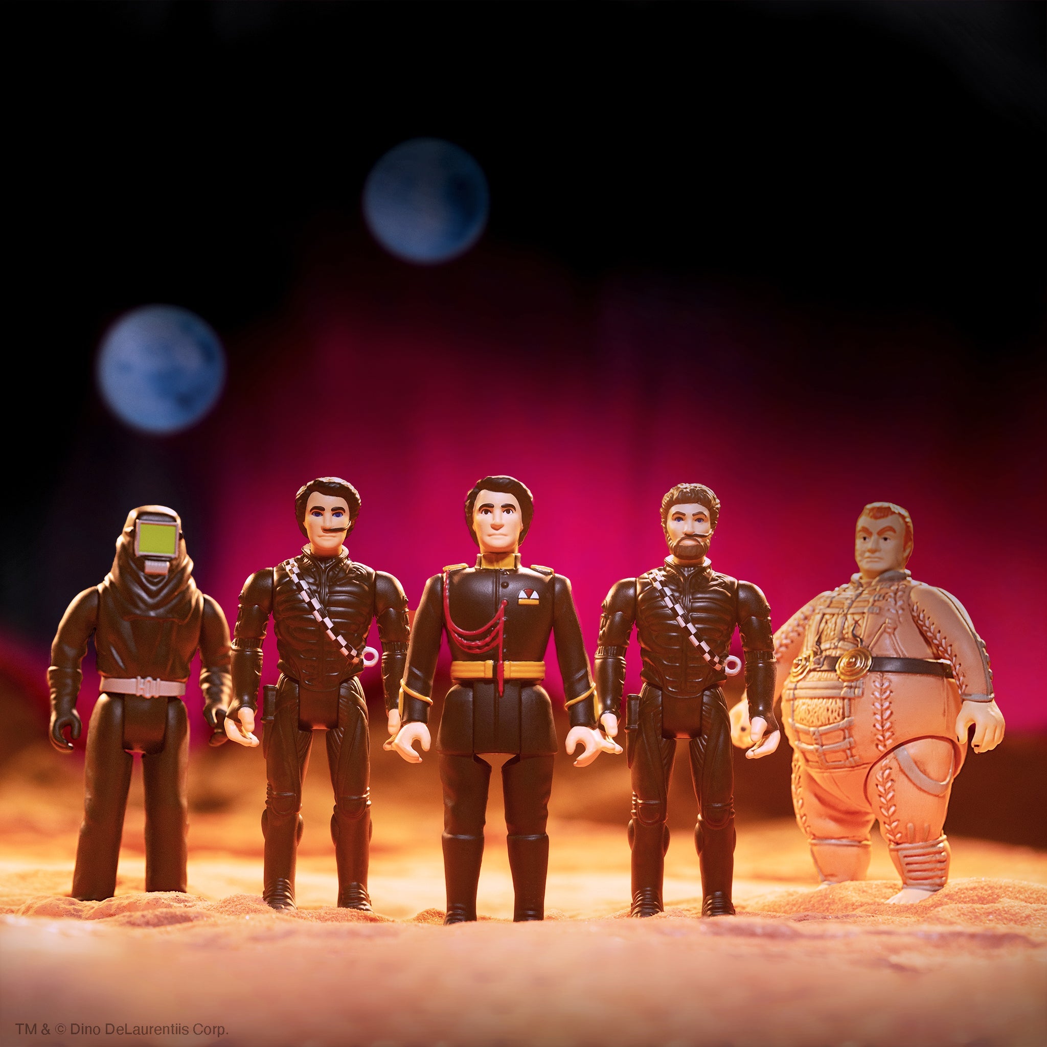 Five fantasy action figures standing in a row on a sandy stage with warm pink lighting