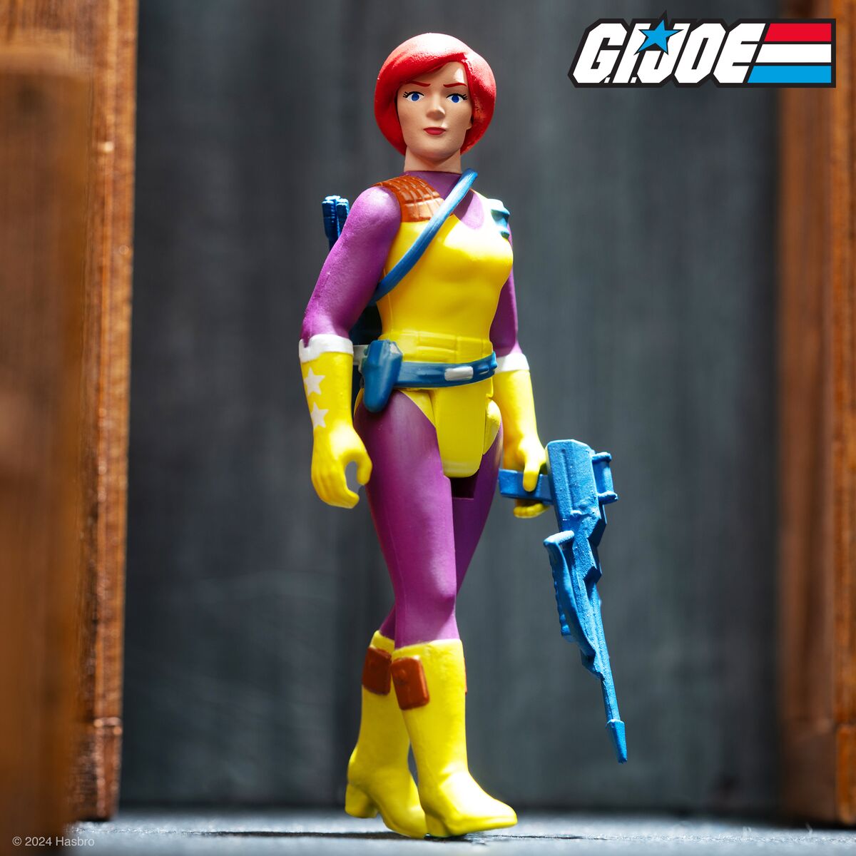 G I Joe style action figure with red hair wearing a yellow and purple outfit and blue weapon at Joe Fest 2024