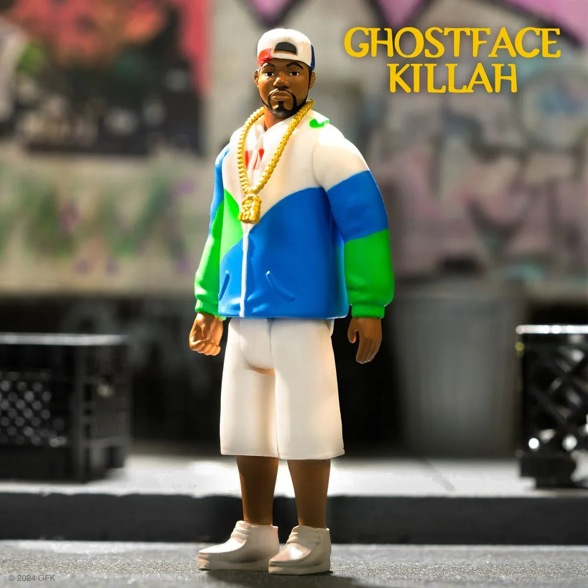 Ghostface Killah action figure in a blue white green jacket and gold chain stands in an urban setting.
