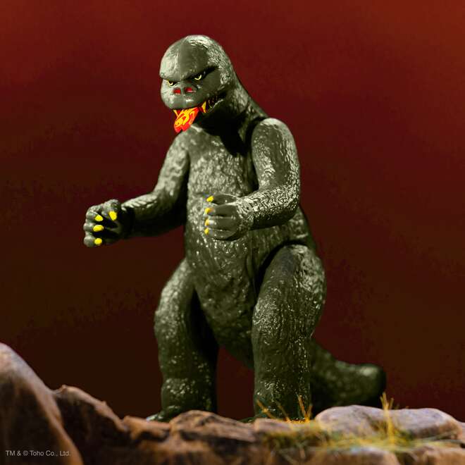 Vintage 70s era kaiju figure with gray textured skin and yellow claws standing on rocky ground.