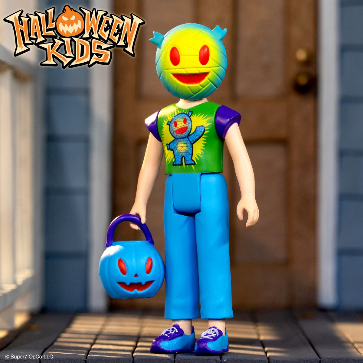 Halloween Kids figure with pumpkin head bright green shirt and blue pants holding a blue pumpkin bucket