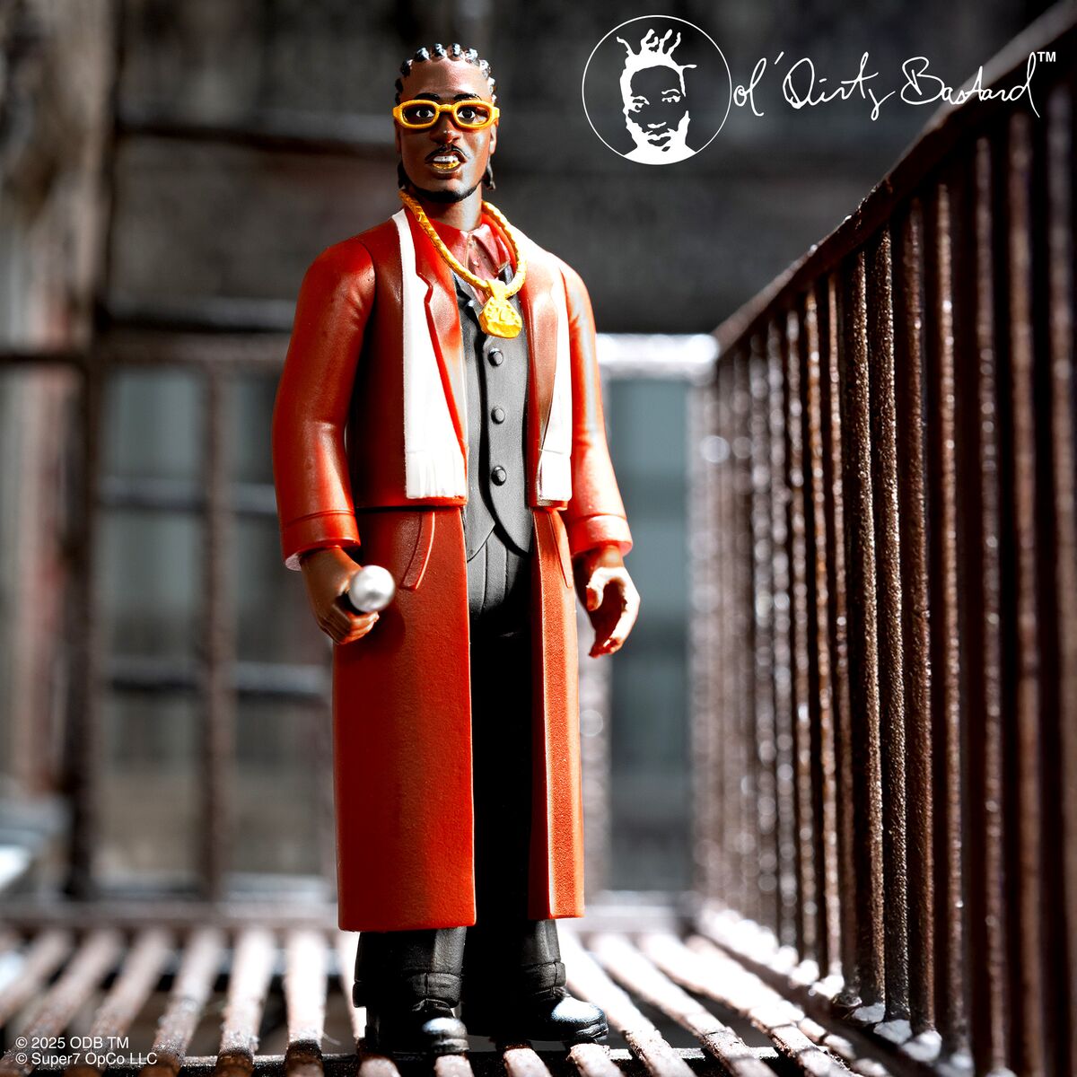 Ol Dirty Bastard figure in an orange coat and yellow sunglasses holding a microphone on a rooftop with an urban backdrop