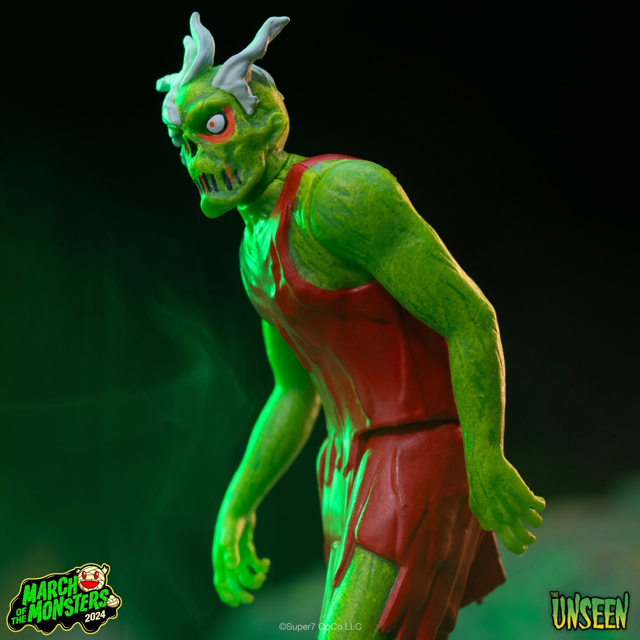 Green horned monster action figure with red eyes under dramatic green lighting in a comic style image.
