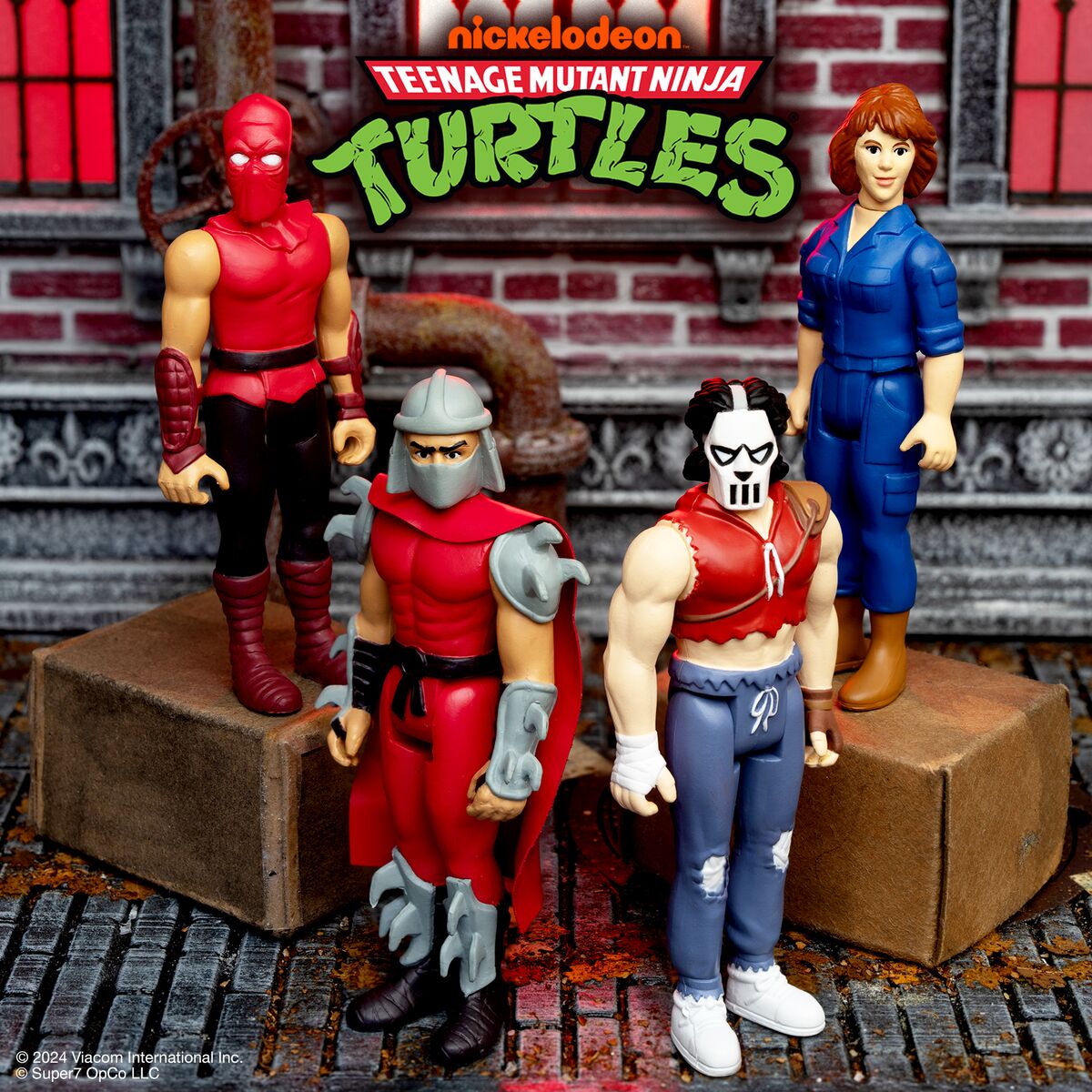90s era Teenage Mutant Ninja Turtles figure set with a red masked hero an armored fighter a masked villain and a blue clad ally against a brick backdrop.