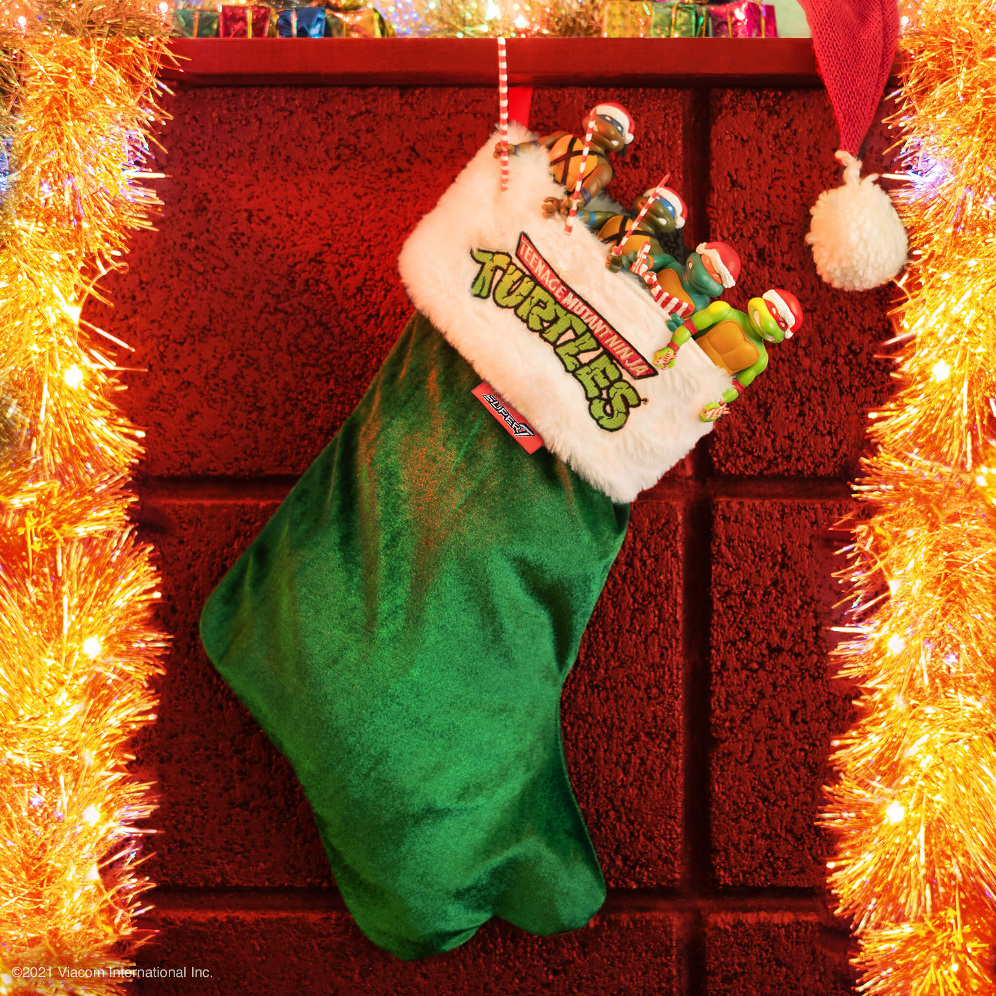Holiday display with a green elf stocking featuring a Teenage Mutant Ninja Turtles patch surrounded by orange tinsel
