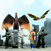 Group of monster action figures in a miniature city scene, including a winged red dragon and gray kaiju.