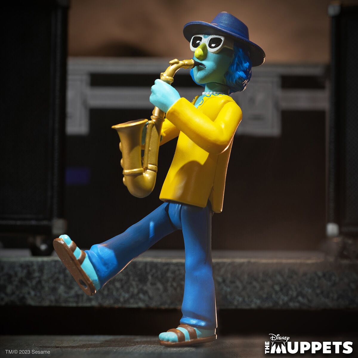 The Muppets character statue playing a saxophone in a yellow jacket and blue pants on stage.