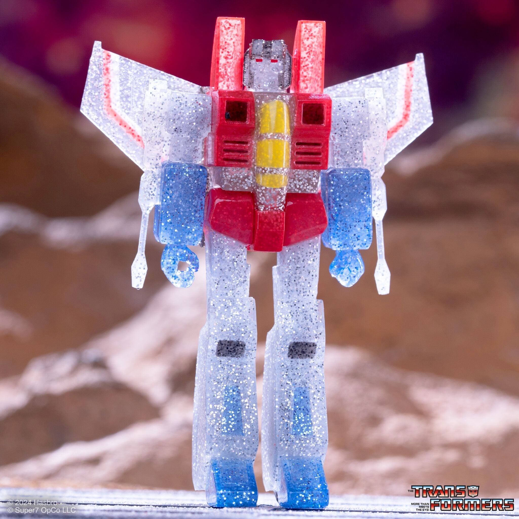 Glittery translucent Transformer robot toy with red and blue parts and outstretched wings.