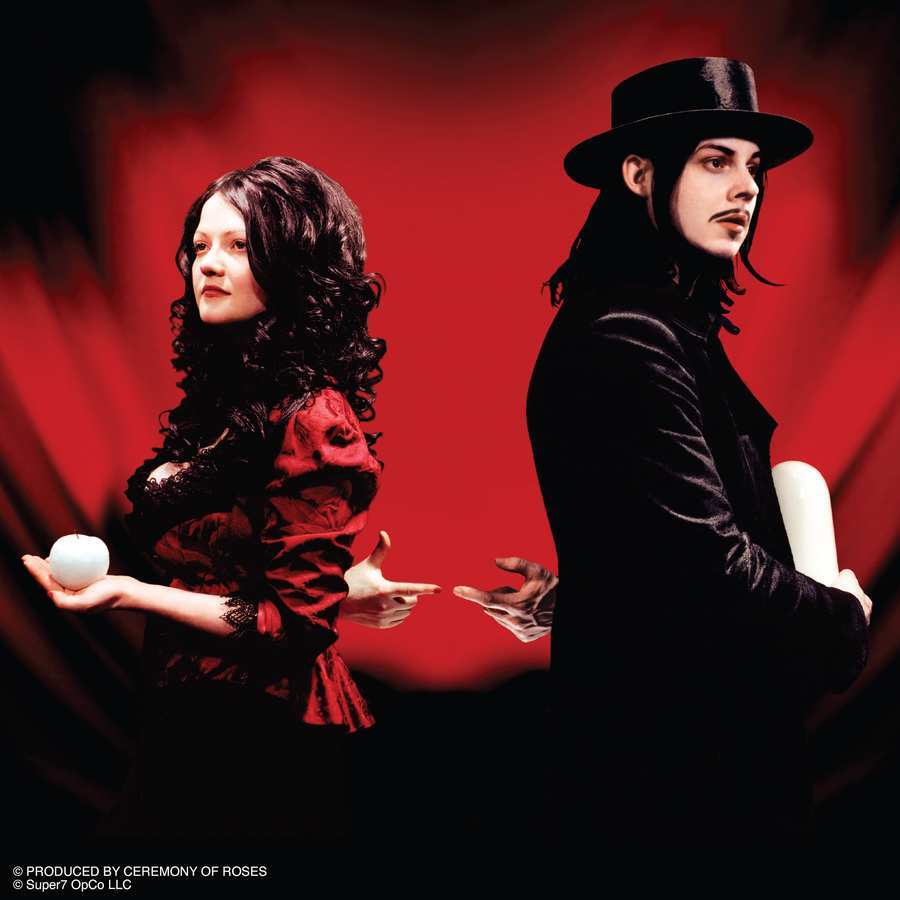The White Stripes duo on a red stage background, Meg White in red and Jack White in a black suit with a top hat