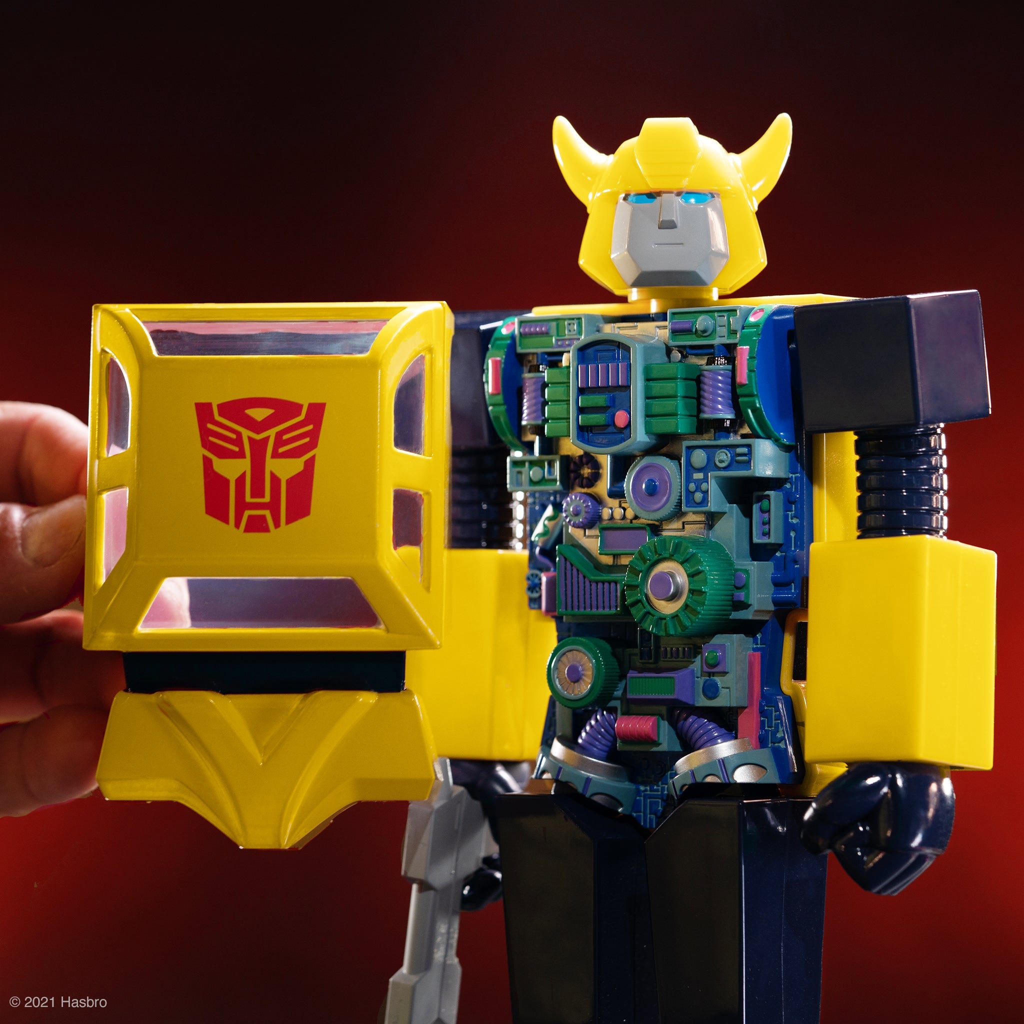 Close up of a bright yellow robotic head with horns and blue eyes, part of a Super Cyborgs toy.