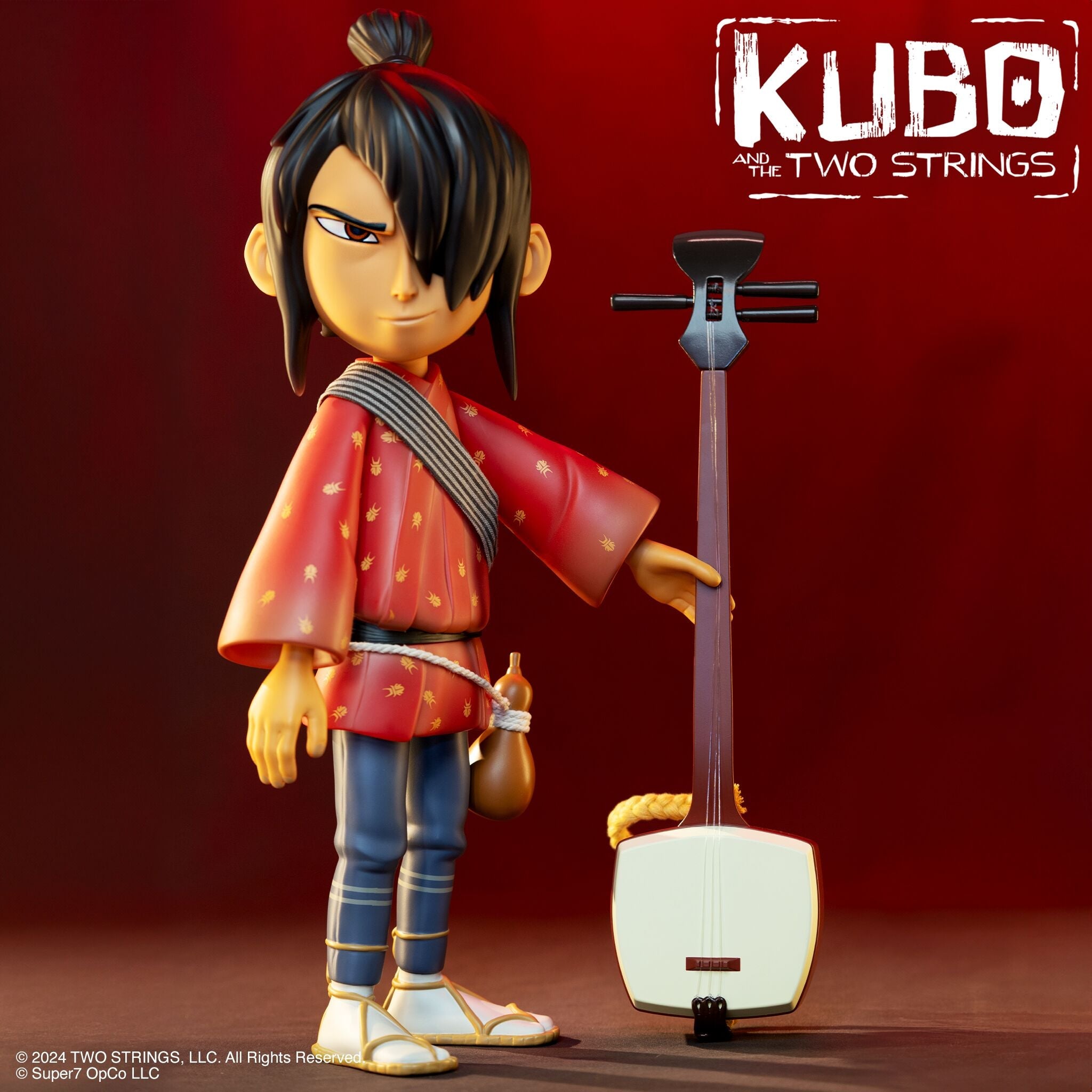 Close up of a stylized samurai action figure wearing a red kimono with black hair and a rope belt against a red backdrop