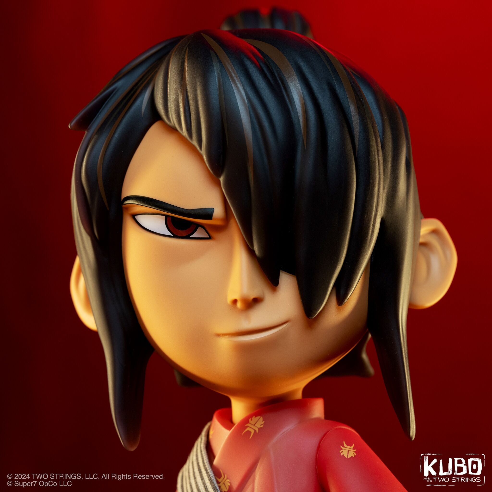 Close up of a stop motion figure head with dark hair against a red background
