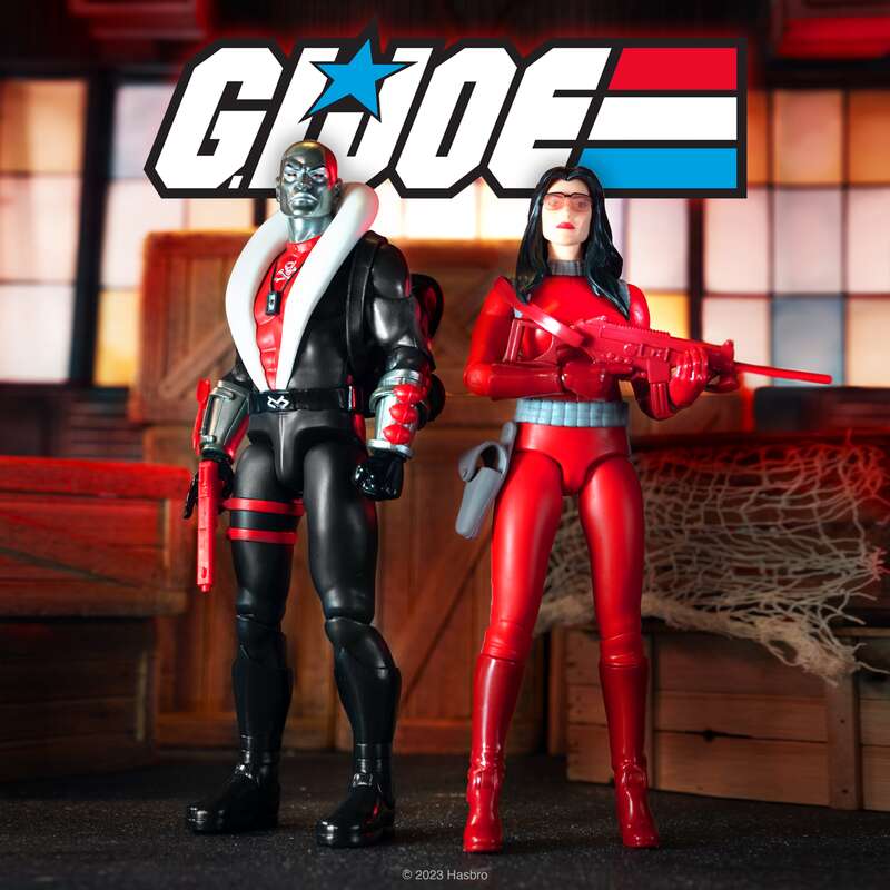 Two GI Joe action figures stand in a staged scene with a large GI Joe logo overhead.