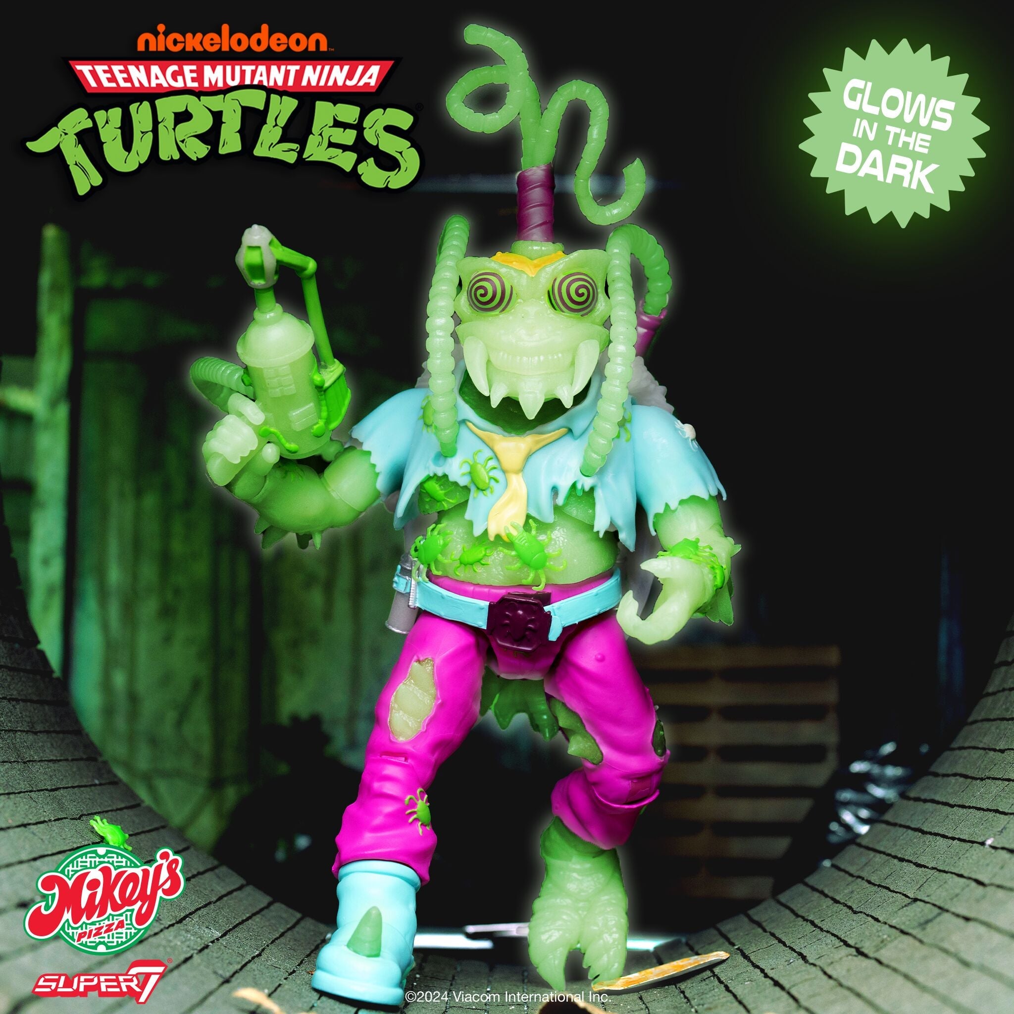 Neon green tentacled mutant turtle figure with pink belt and blue pants on a dark display