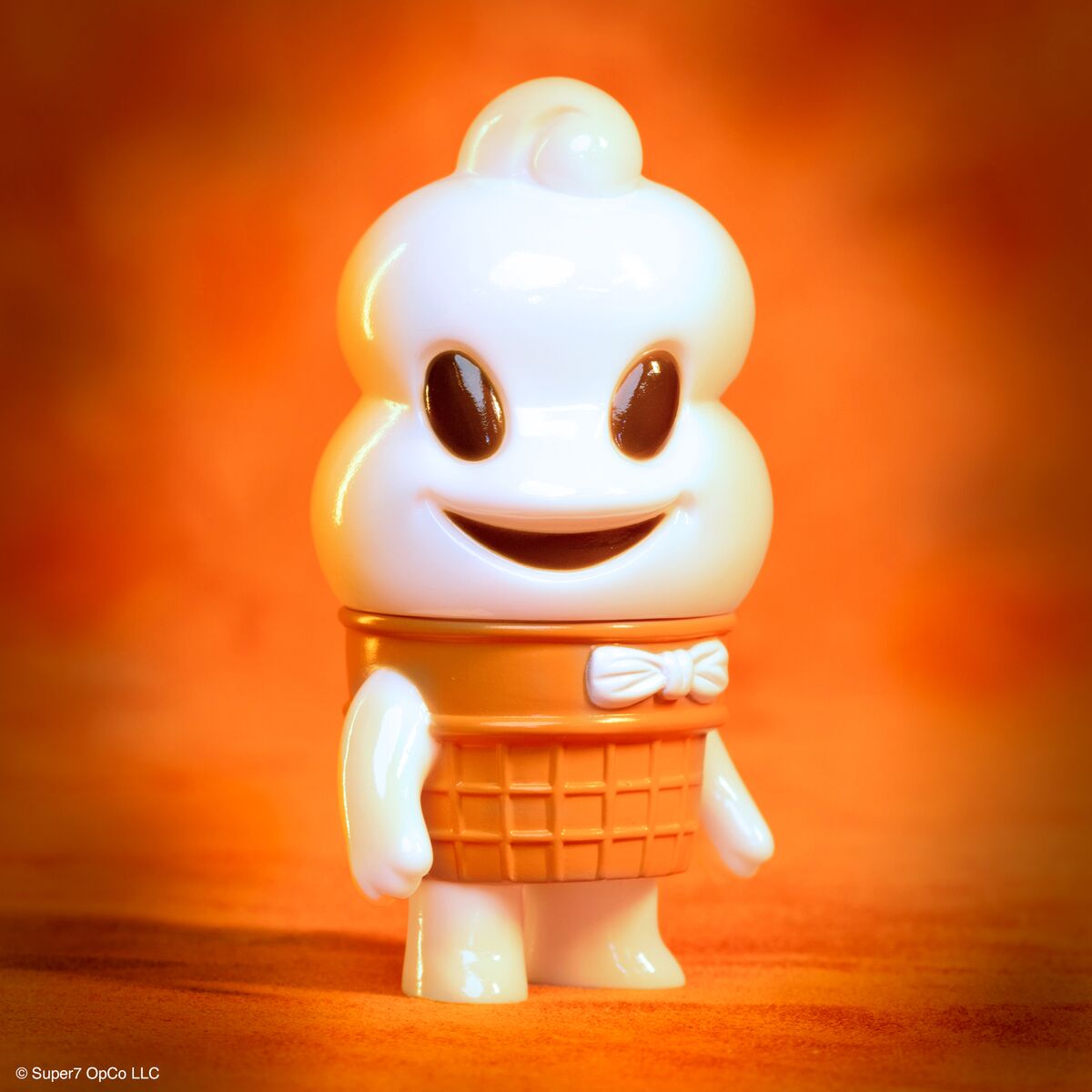 Kandy Kaiju toy with an ice cream cone torso and bow tie against a warm orange backdrop