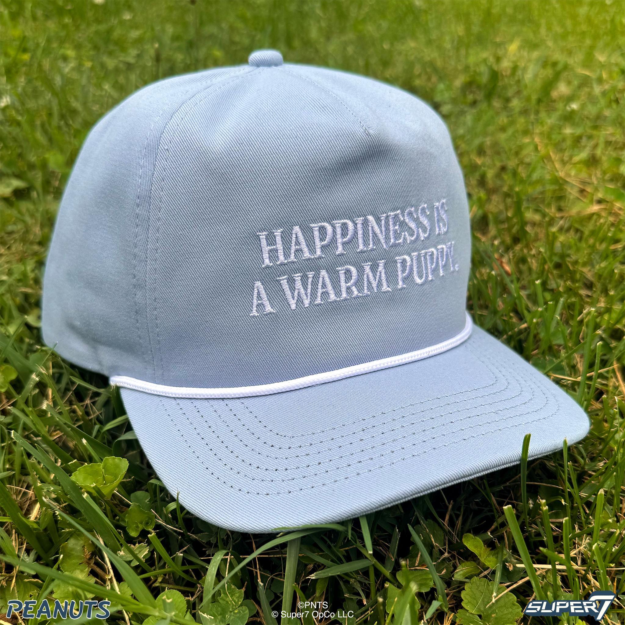 Light blue Happiness Hat with embroidered slogan on the crown resting on grass.
