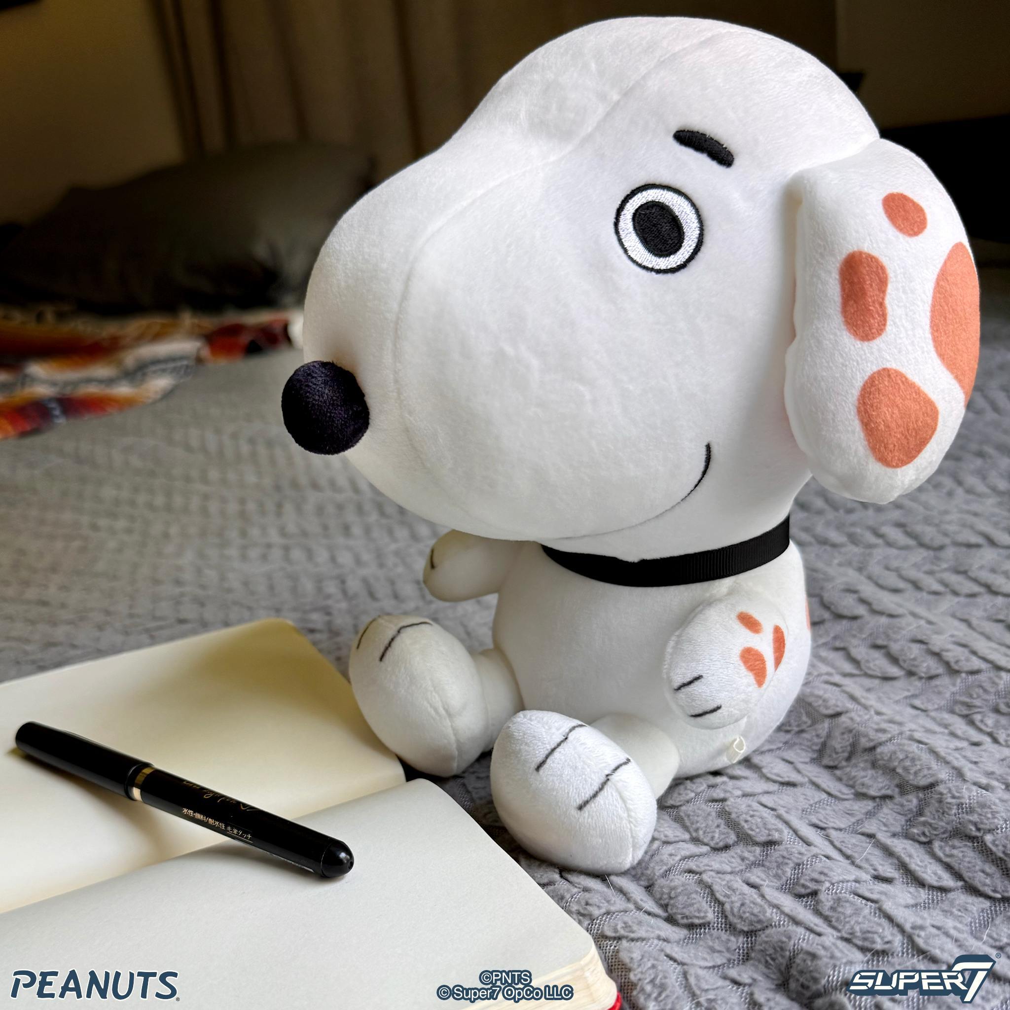 Close up of a white Peanuts plush dog with orange spotted ears and a black nose