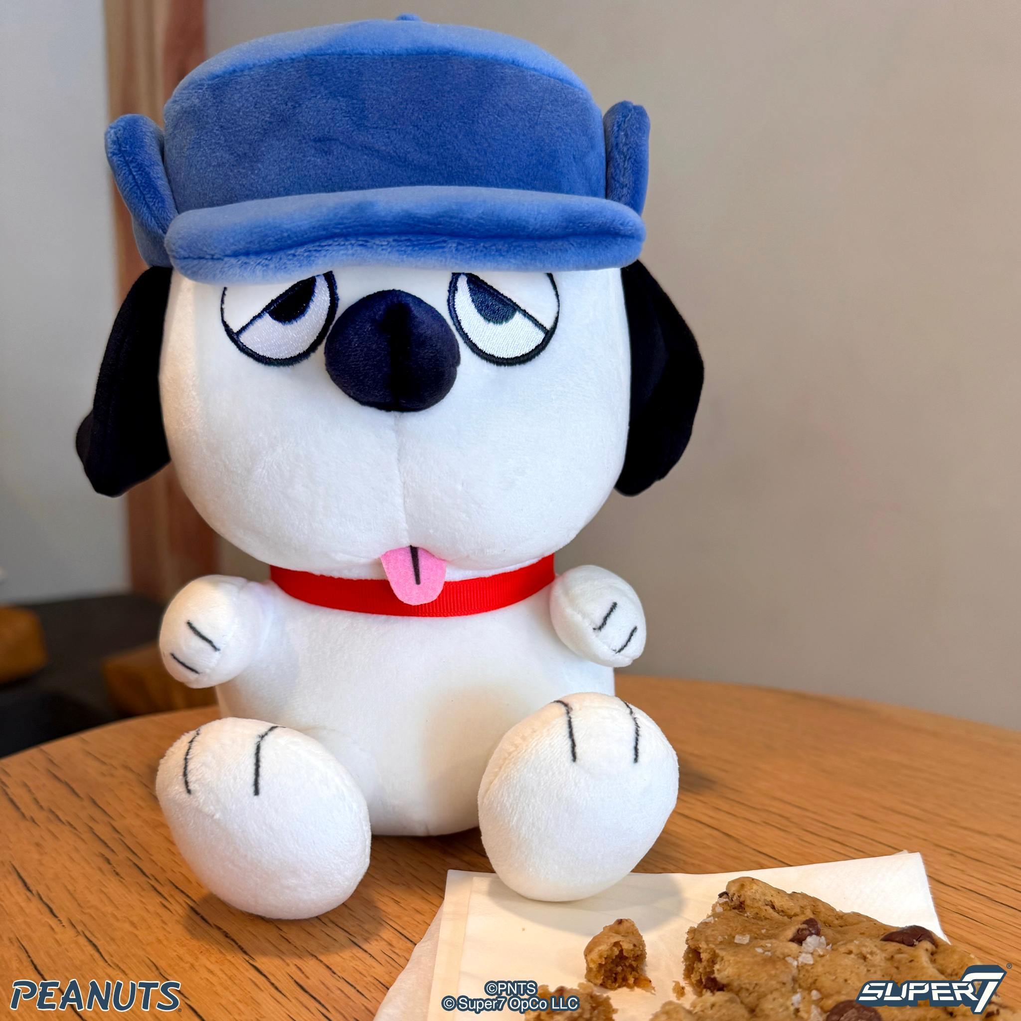 Olaf Peanuts plush wearing a bright blue hat, close-up of face on a wooden table.