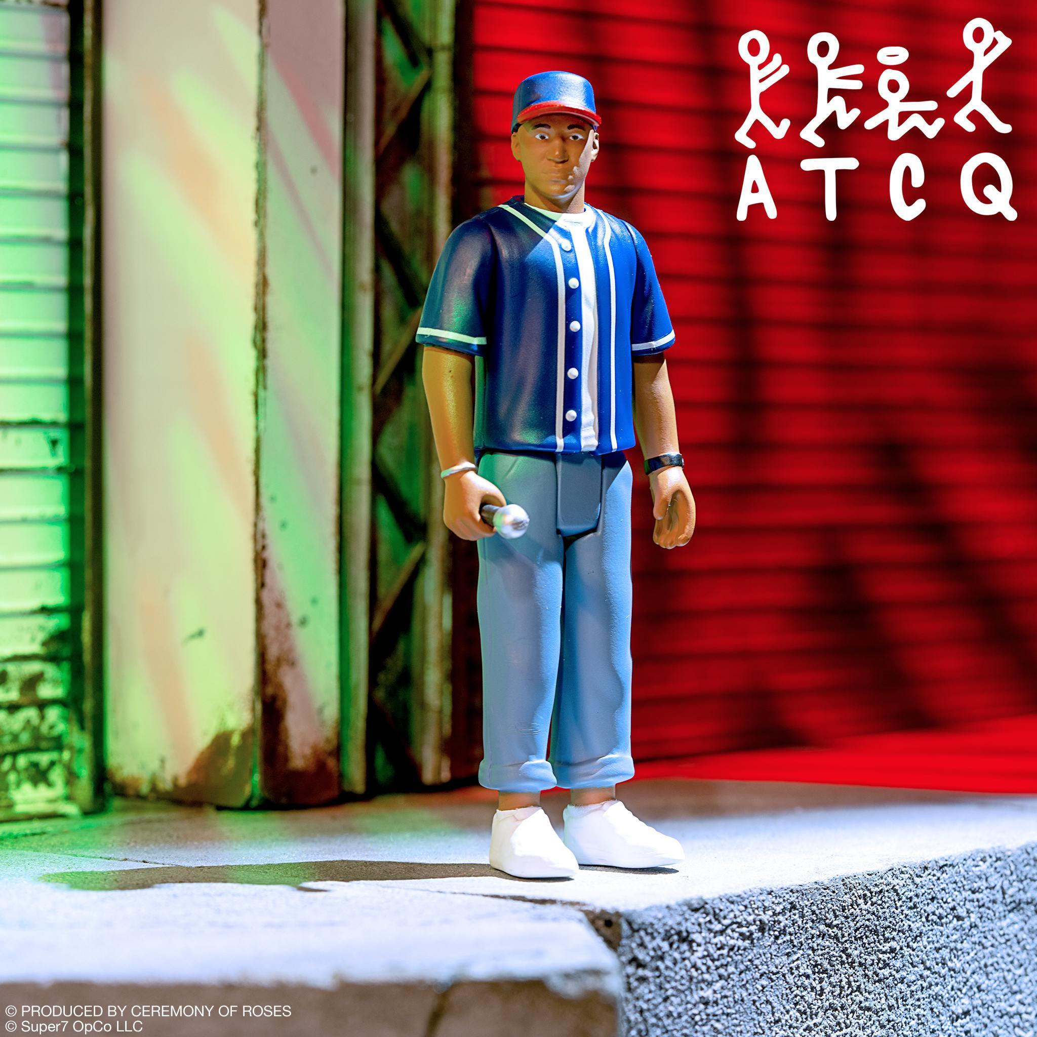 A Tribe Called Quest Wave 2 Q-Tip ReAction Figure in blue baseball jersey holding a microphone, urban backdrop