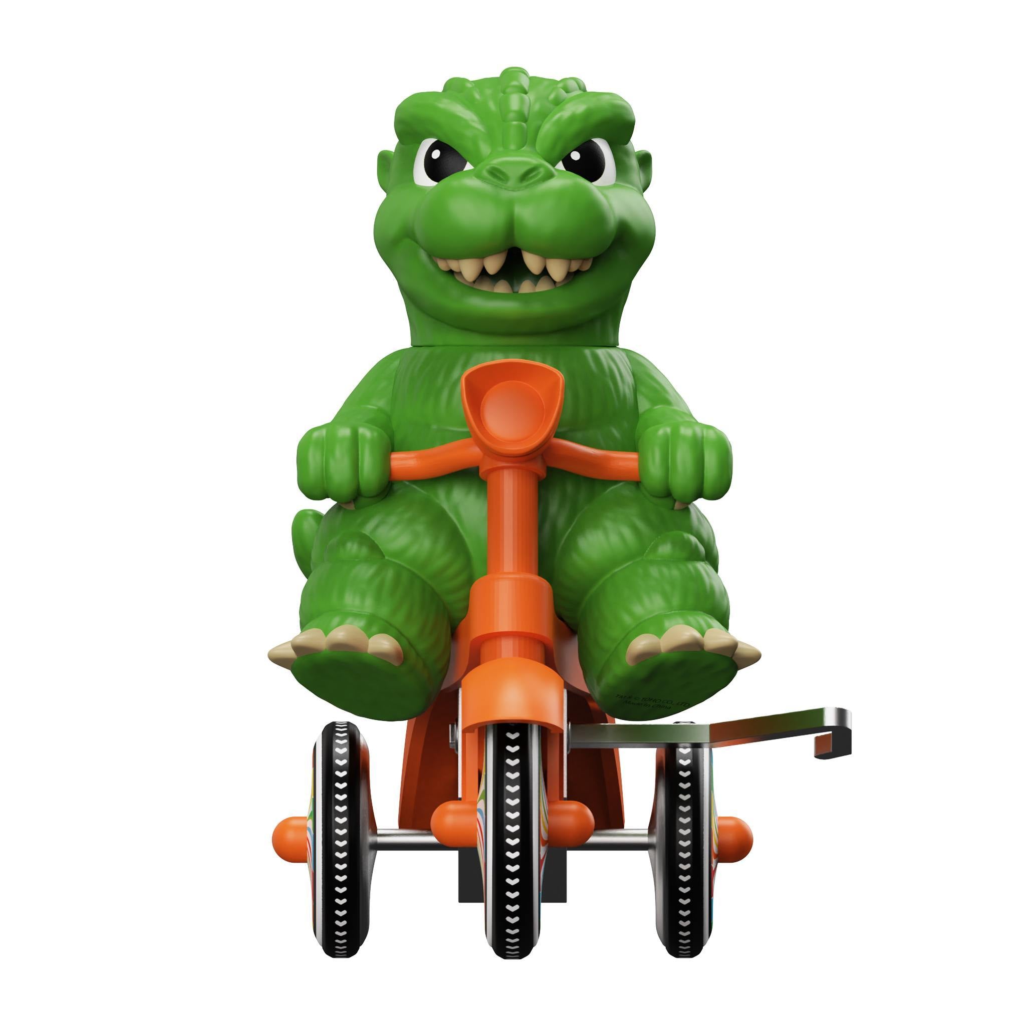Full body view of the green Godzilla figure riding a red tricycle with a city backdrop