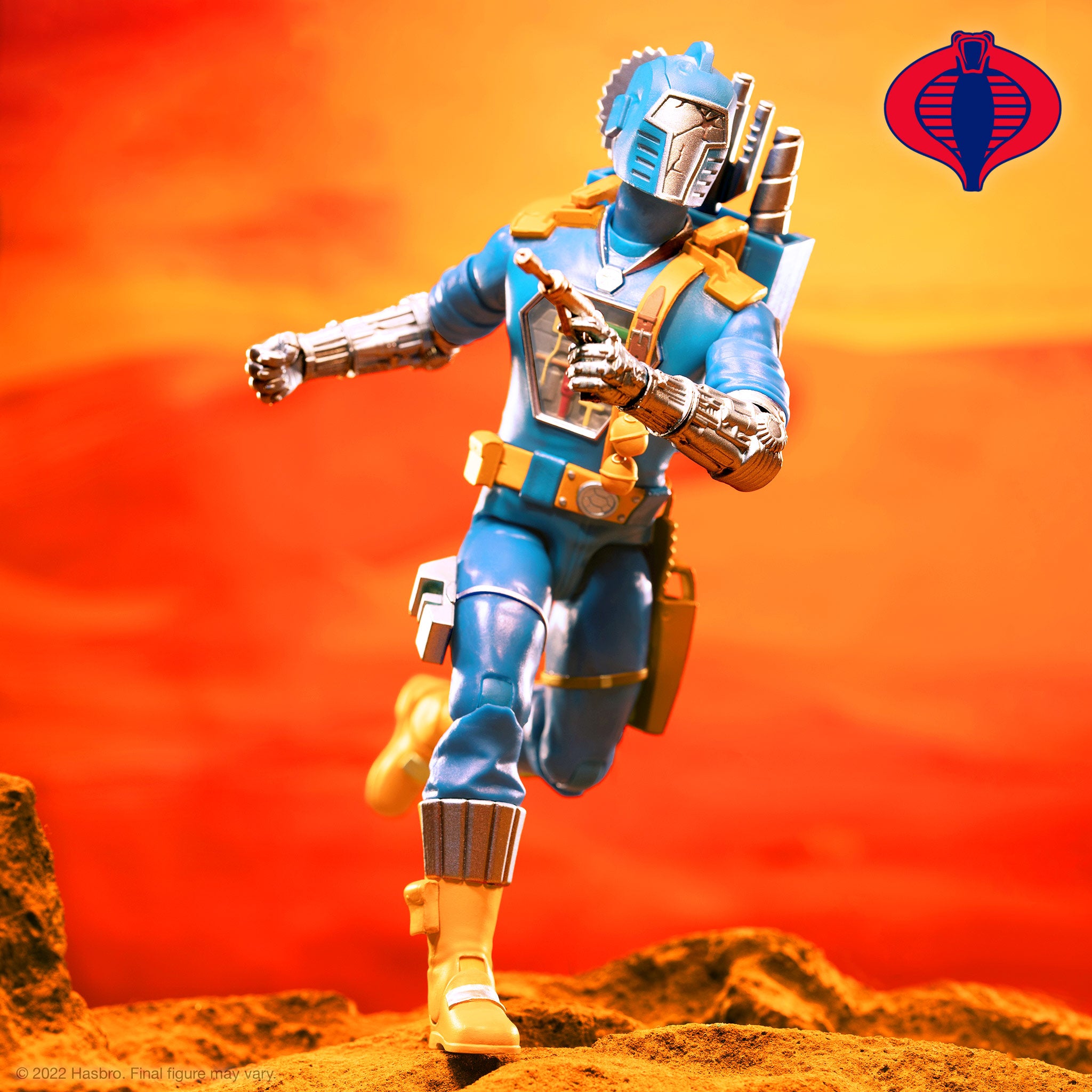 Cobra B.A.T. figure posed on rocky orange terrain against a fiery sky with Cobra emblem in the top right