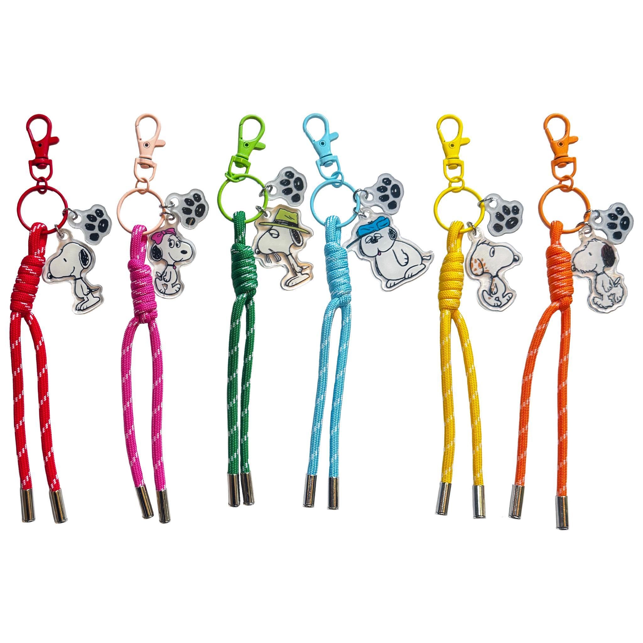 Close up of multicolored cord bag lanyards with metal tips and Snoopy paw print charms against a white background.