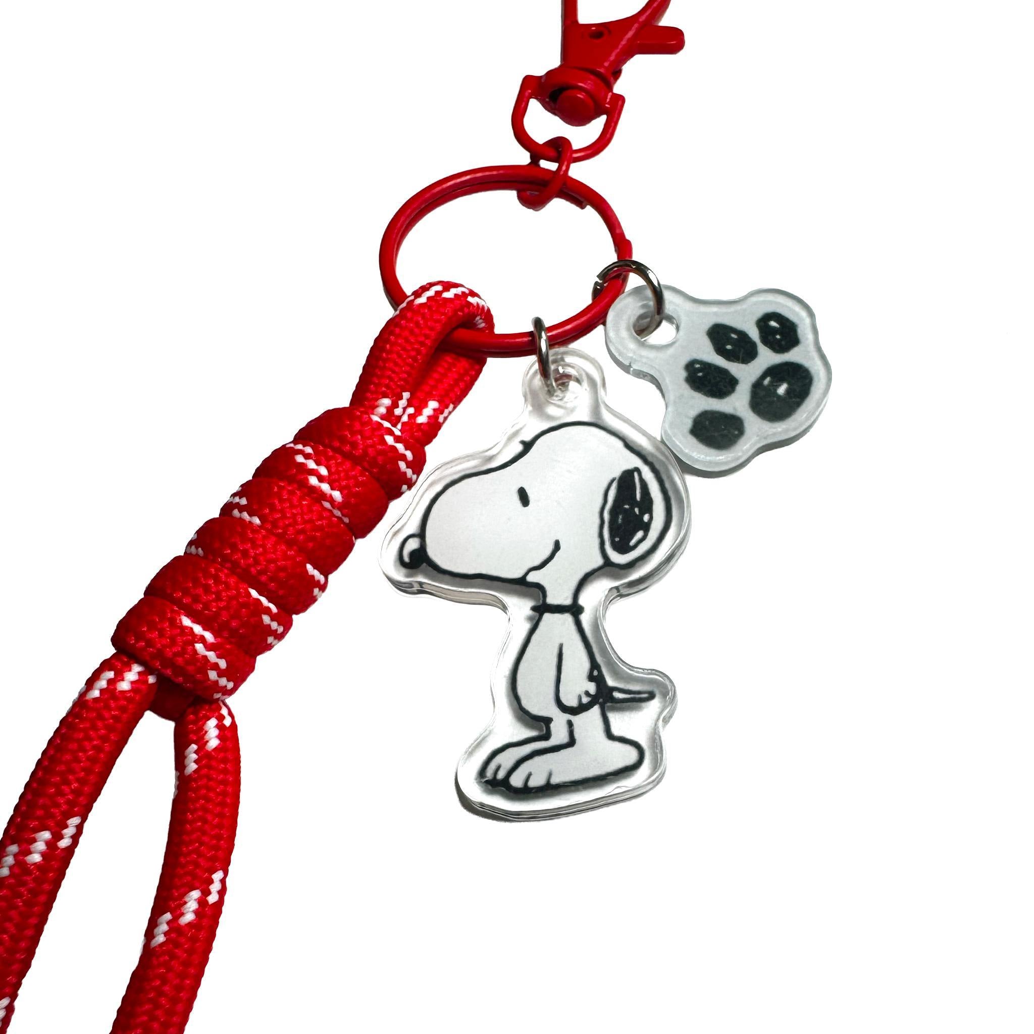 Row of colorful Peanuts bag charms on a white background with Snoopy paw print charms in red peach pink green blue yellow and orange.