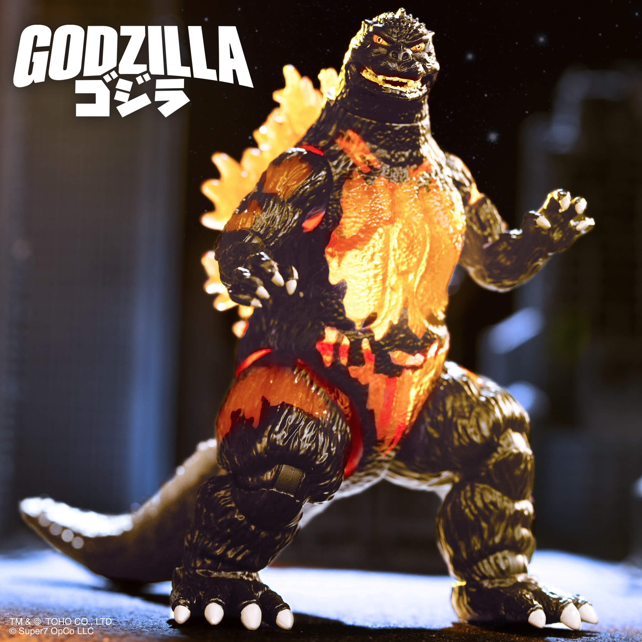 Close up of Burning Godzilla figure from Toho Super Kaiju Wave 02 with fiery texture and flames on the torso near stacked white bricks.
