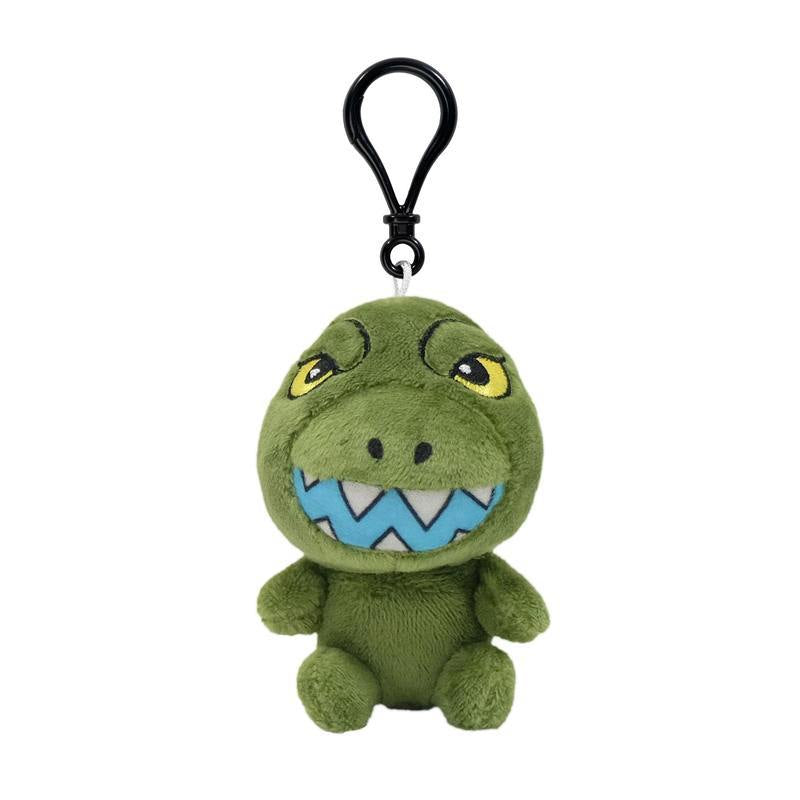 Front view of a green dinosaur plush keychain with yellow eyes and a blue zigzag mouth, attached to a black clip.