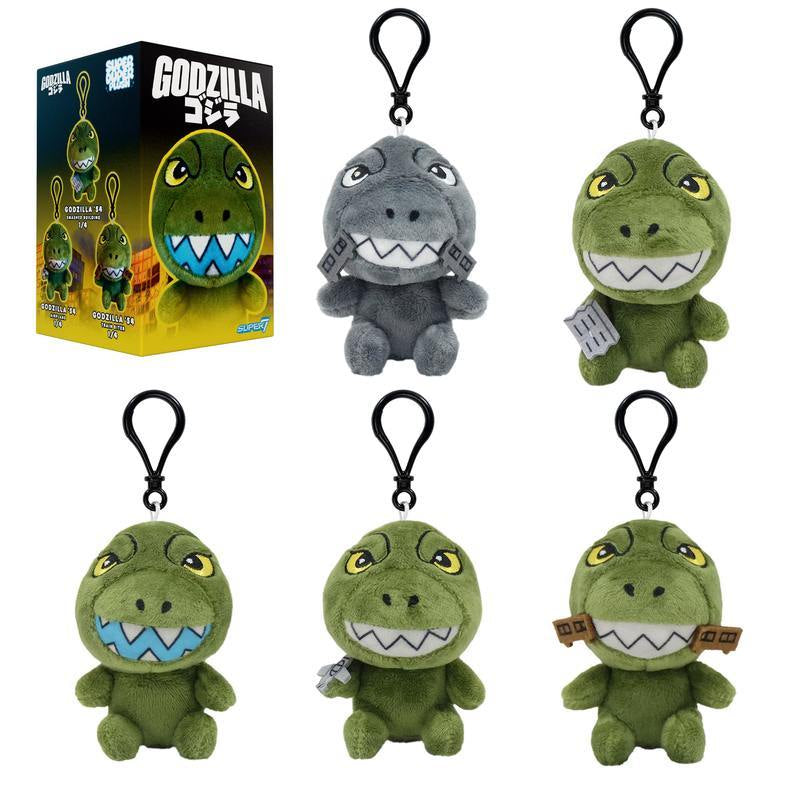 Six Godzilla plush keychains with loop attachments beside a boxed display of the product
